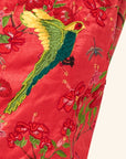 Embroidered fabric with a bird and floral design on a red dress closeup