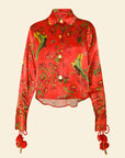 Red floral blouse with green leaves and red tassels on a beige background