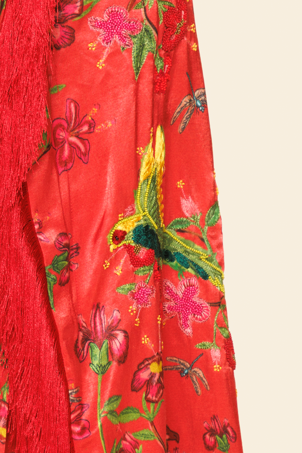 Red fabric with floral and bird embroidery on a beige background
