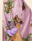 Close up image of person wearing purple blouse with tiger prints and floral decorations