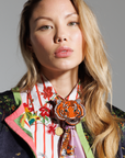Woman wearing a colorful outfit with a prominent tiger brooch in a studio setting