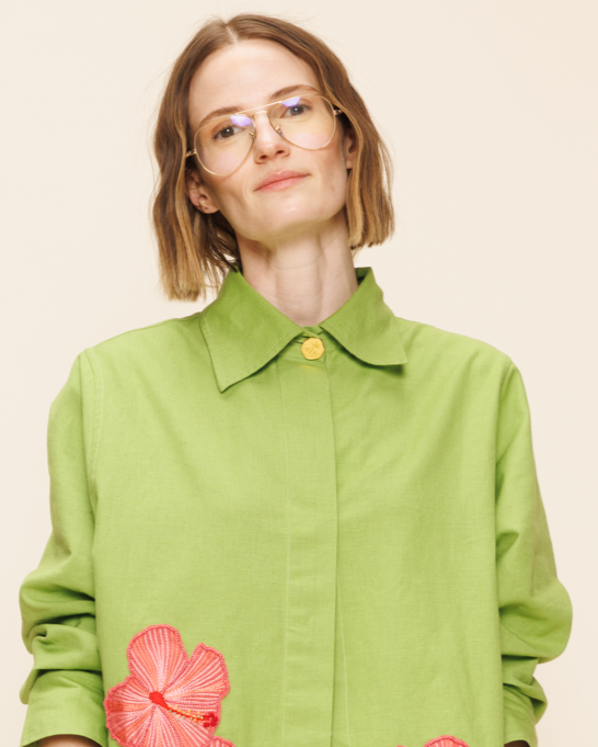Woman wearing a green outfit with floral details on a beige background