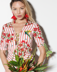 Woman in a red and white floral dress holding a bouquet of flowers against a white background
