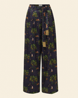 A pair of pleated trousers with a printed design featuring what appears to be a tropical landscape, paired with an embellished belt with fringe.
