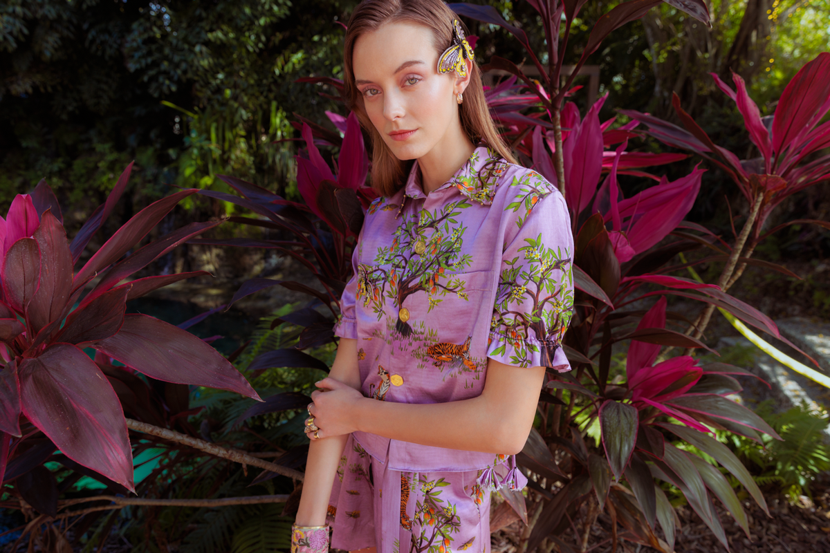 Woman in a purple floral dress standing among tropical plants