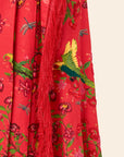 Red fabric with green and yellow bird pattern and red fringe
