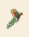 Embroidered brooch with parakeet design on a beige background