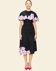 Woman wearing a black skirt and cape with floral appliqué