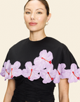Woman wearing a black cape with pink floral appliqué