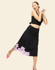 Woman in a black outfit with floral details on a beige background
