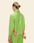 Person wearing a green outfit with pink floral details on a beige background