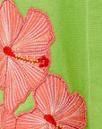 Embroidered pink flowers with red centers on a green fabric background