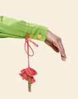 Hand holding a pink floral keychain against a light beige background.