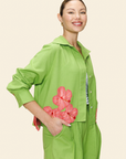 Woman wearing a green shirt and pants with pink floral accents on a beige background