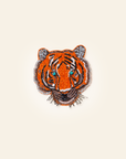 Embroidered tiger brooch on a beige background