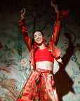 Person wearing a red outfit with floral patterns against a decorative wall.