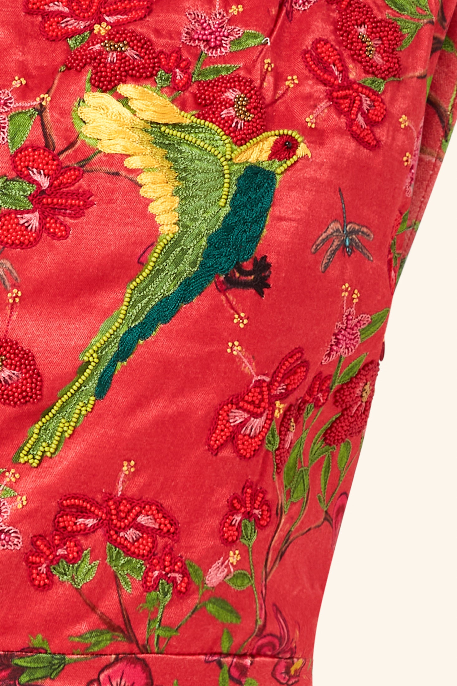Embroidered fabric with a bird and floral design on a red dress closeup
