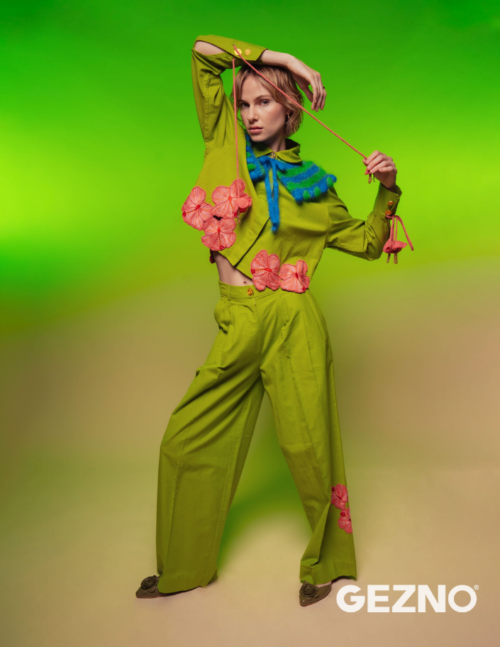 Person wearing a green Ashaki outfit with floral details against a green gradient background.