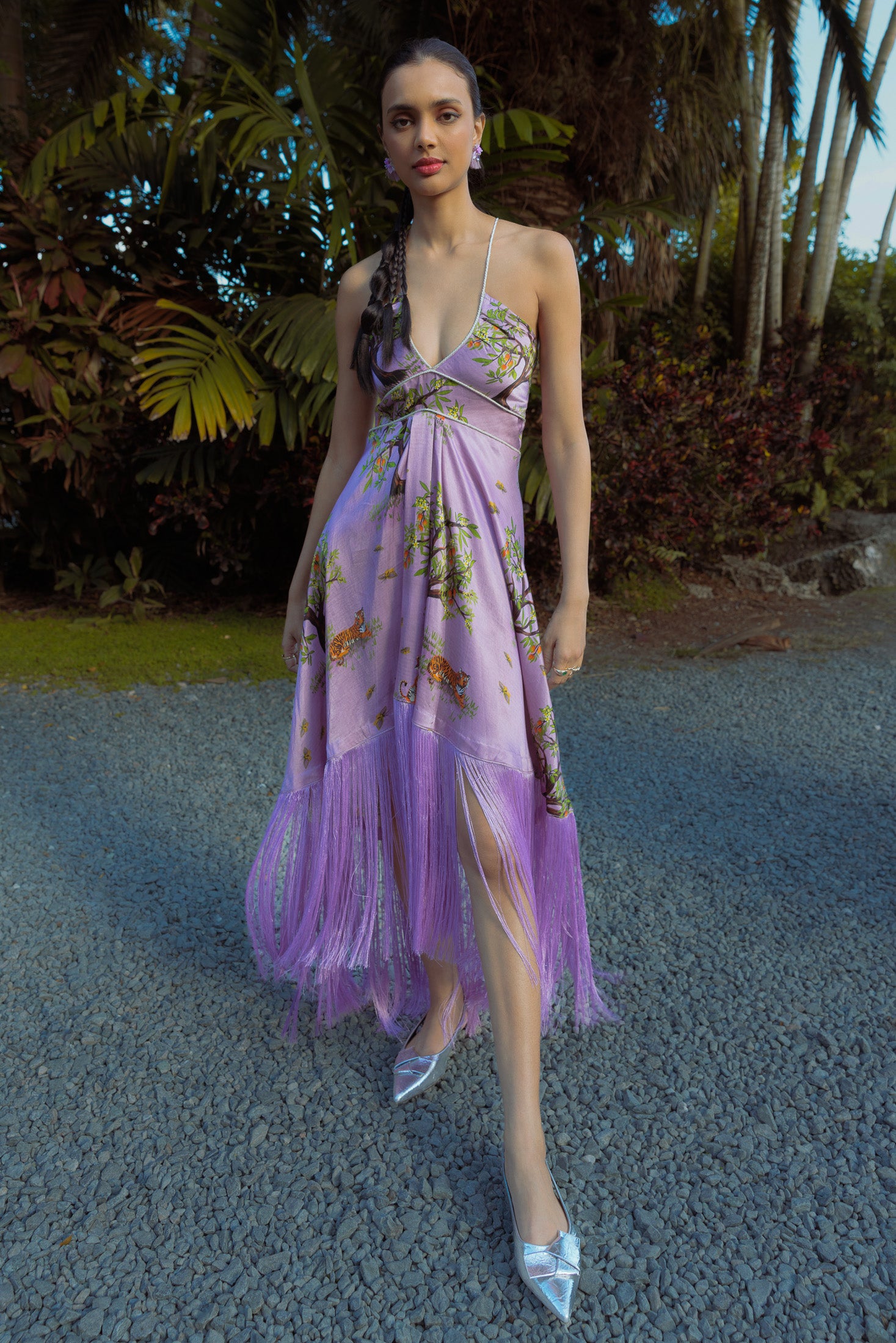 Woman wearing a purple floral dress with fringe details outdoors.