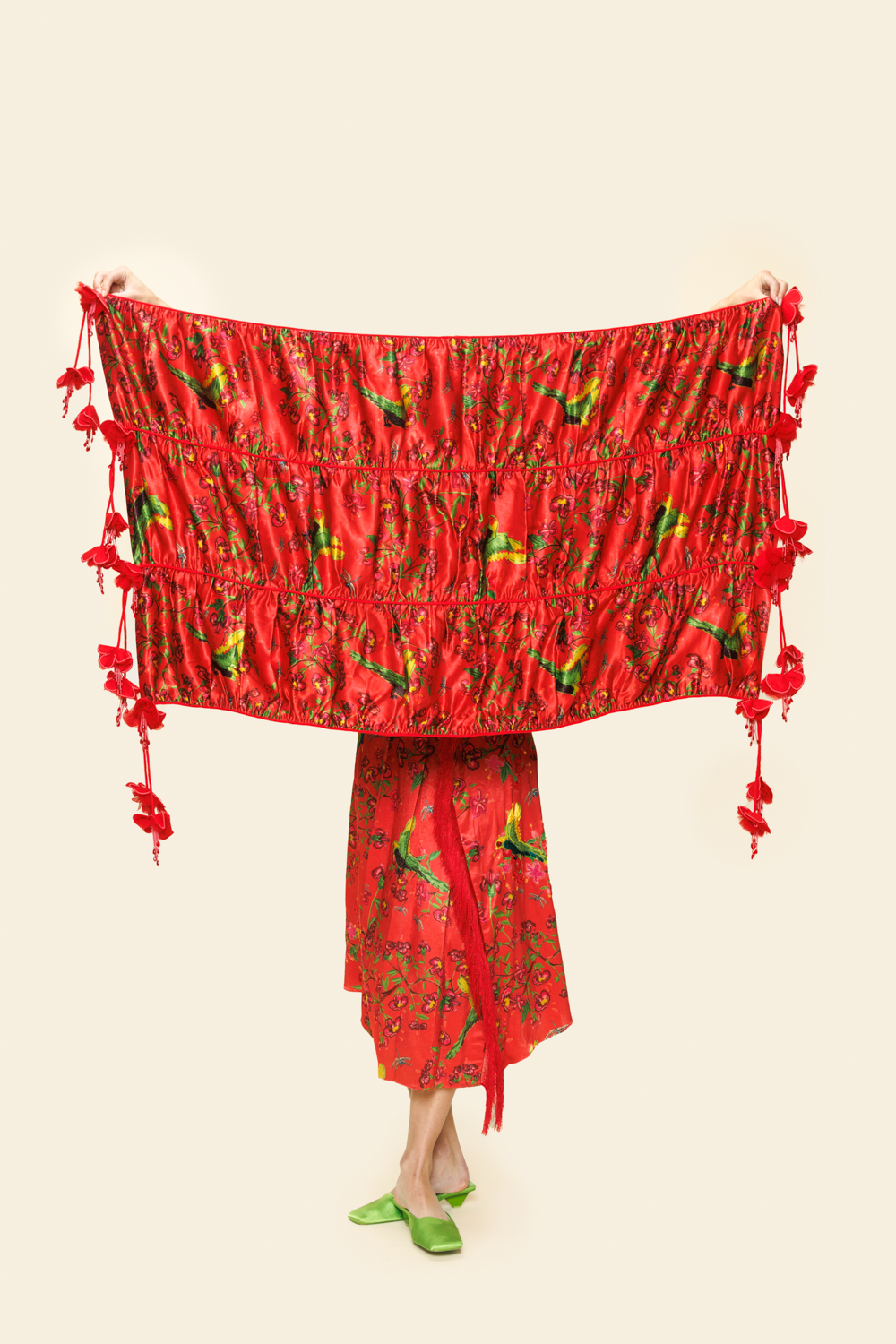 Person Holding up red scarf with florals, tassels and green parakeets