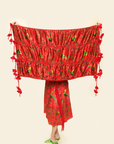 Person Holding up red scarf with florals, tassels and green parakeets