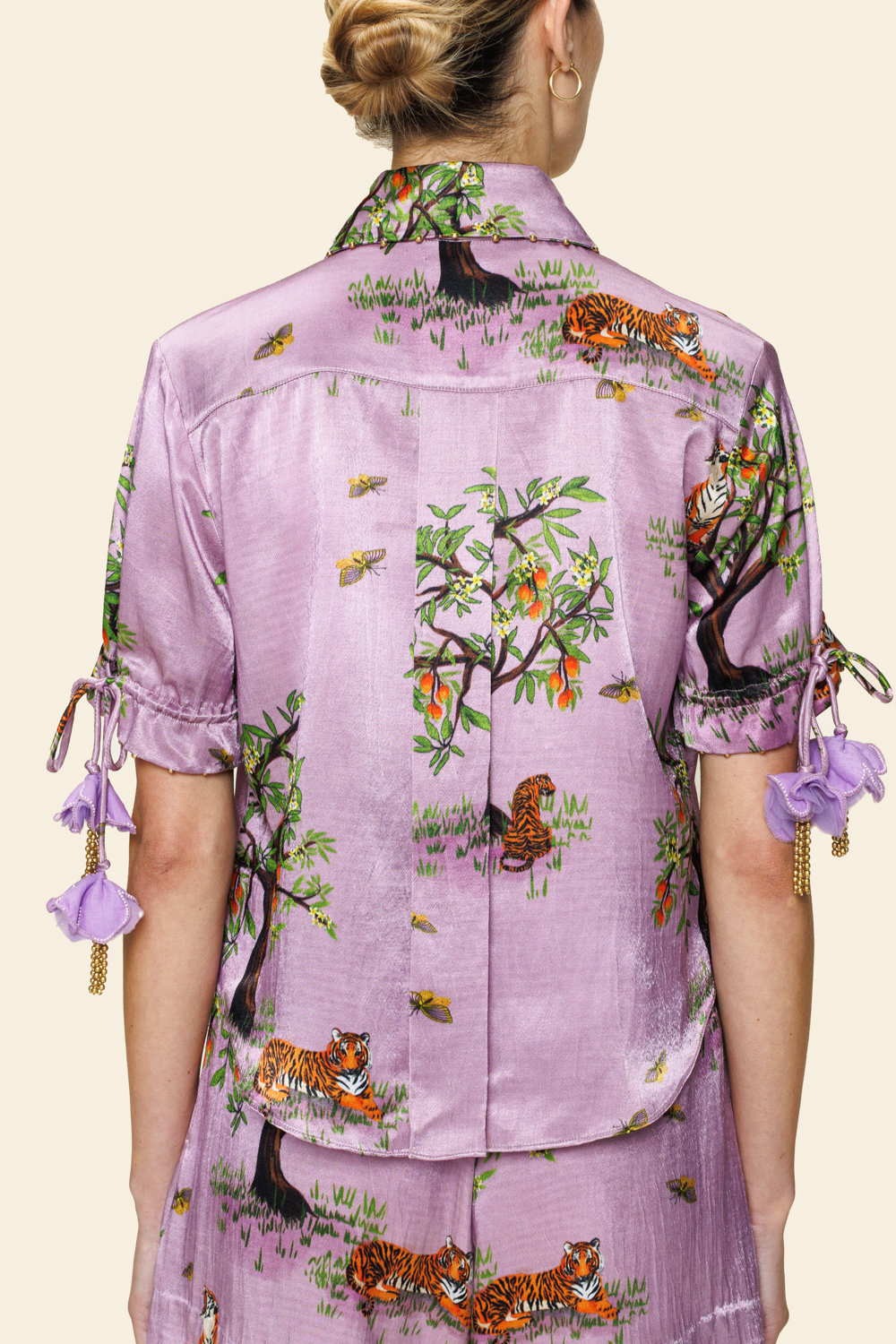 Person wearing a purple floral shirt and shorts on a light background shot from the back