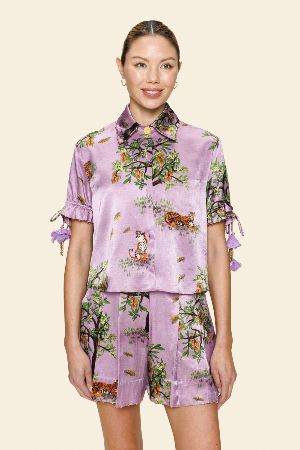 Person wearing a purple floral shirt and shorts on a light background