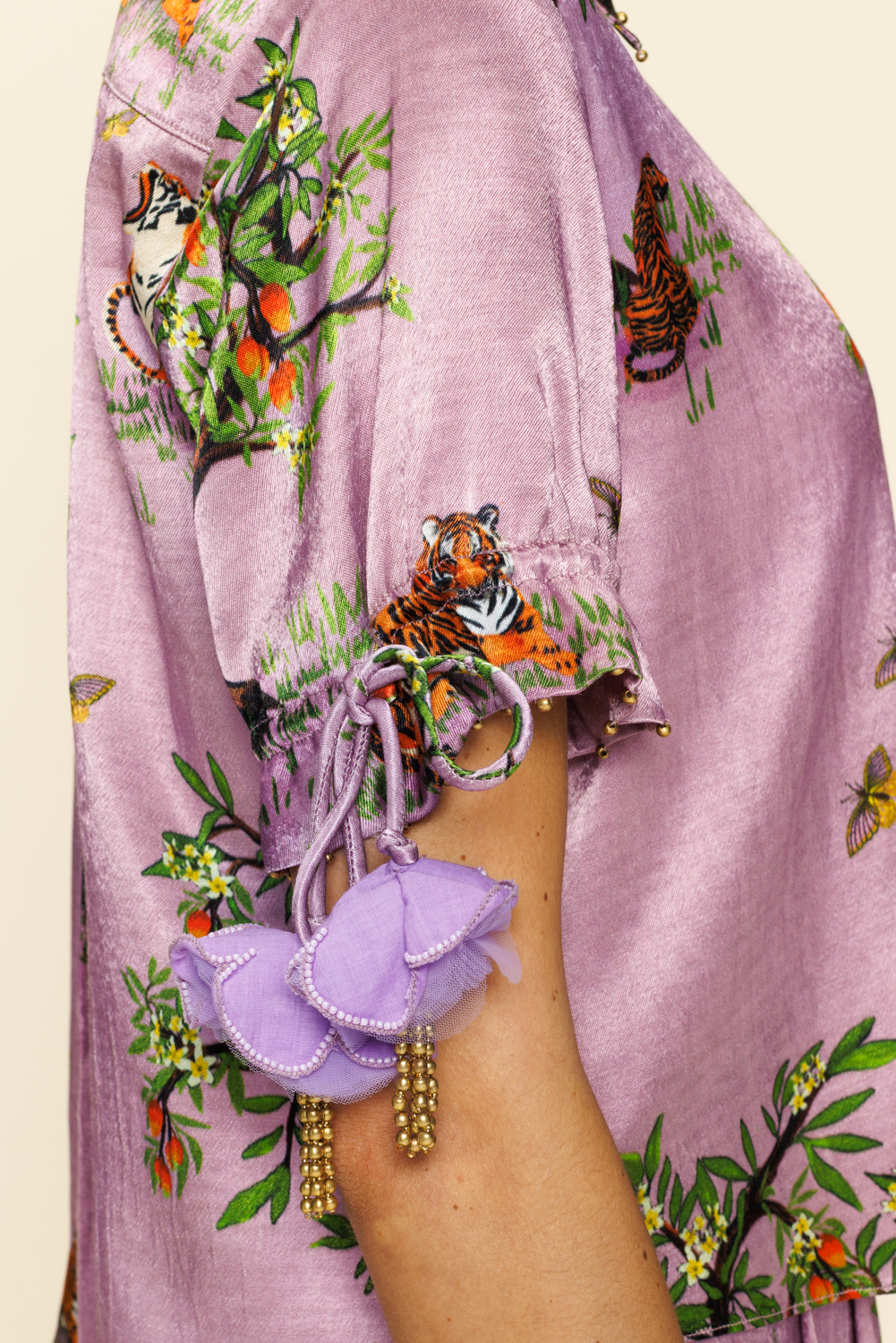 Close up image of person wearing purple blouse with tiger prints and floral decorations