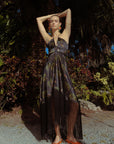 Woman in a dark dress standing in a garden with palm trees
