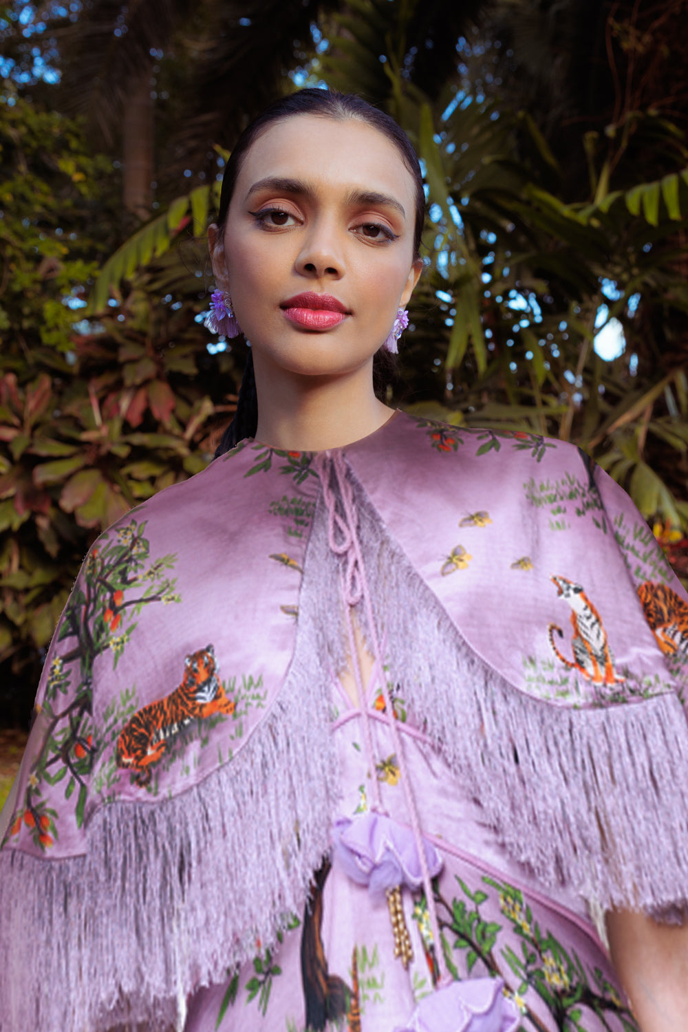 Woman wearing a purple embroidered shawl with tigers in a natural setting