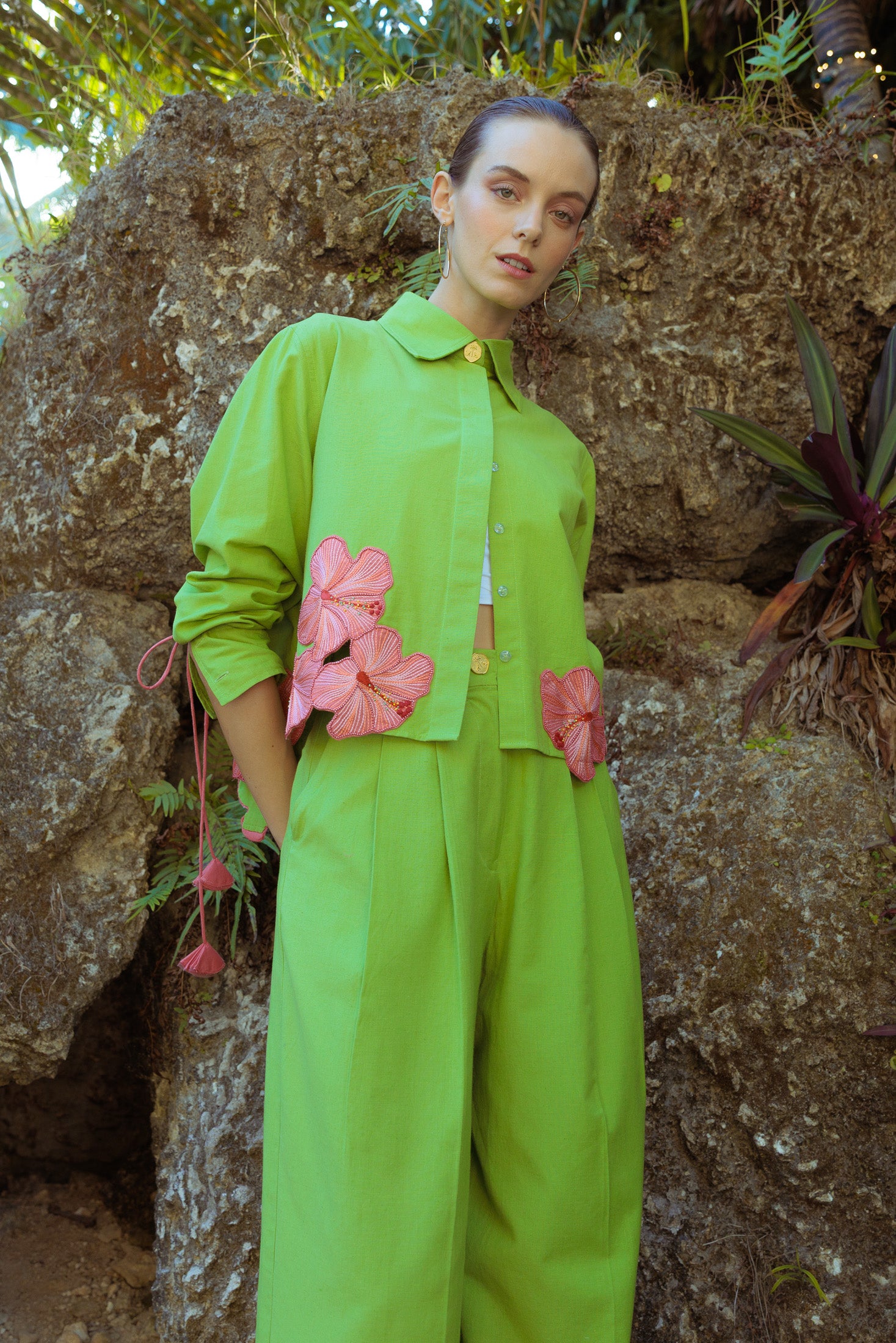 Person wearing a bright green outfit with pink flowers against a natural background