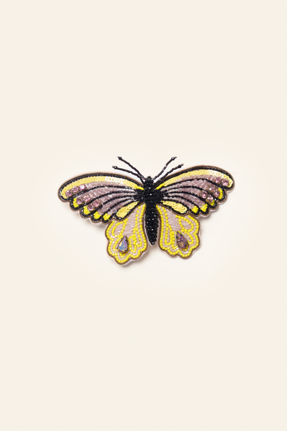 A brooch depicting a yellow and black butterfly with intricate details on a white background.