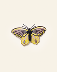A brooch depicting a yellow and black butterfly with intricate details on a white background.