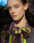 Woman wearing a colorful blouse and jacket with a butterfly accessory