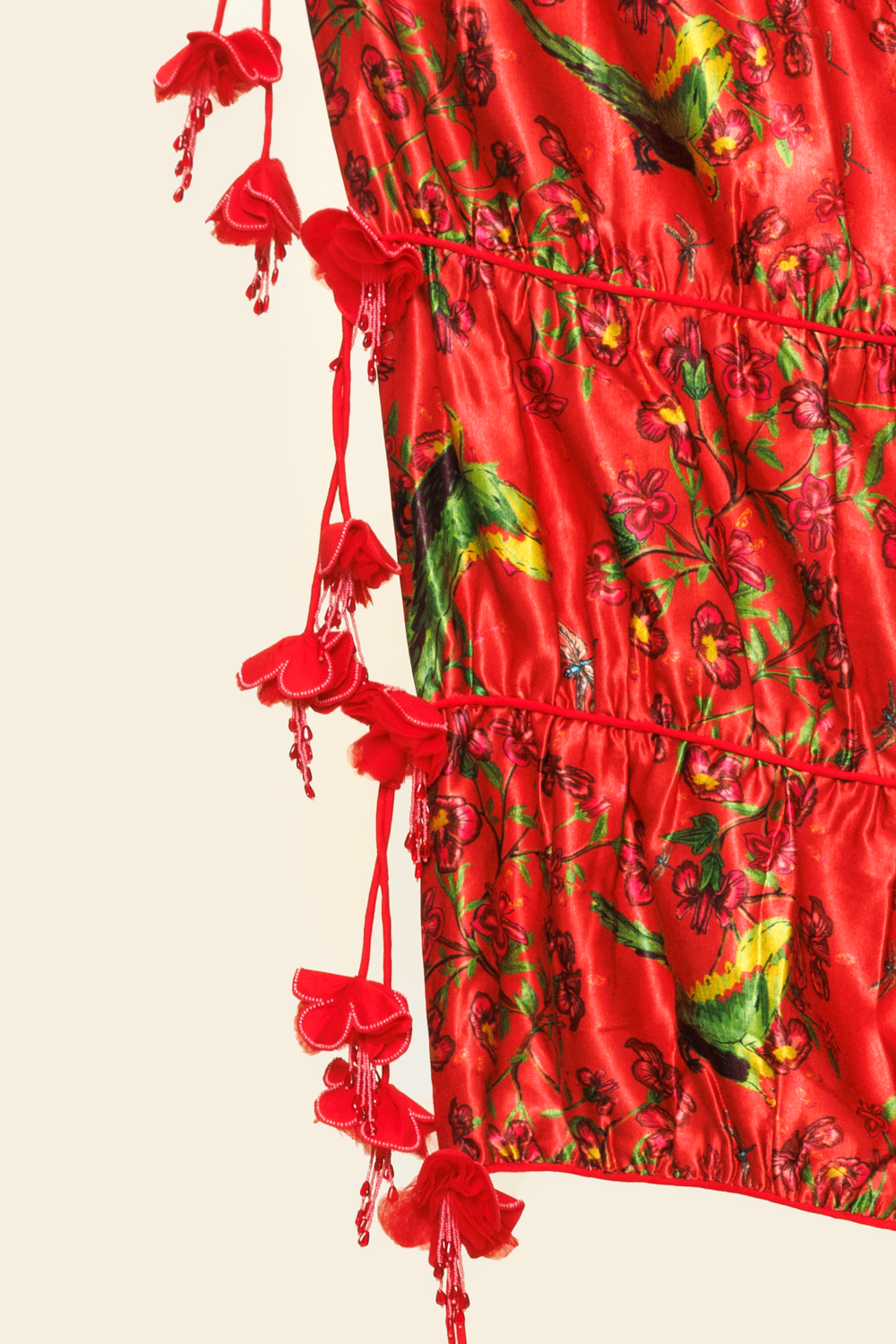 Red dress with floral pattern and tassels on a beige background