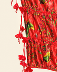 Red dress with floral pattern and tassels on a beige background