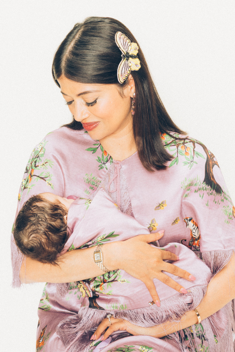 Woman in a floral dress and butterfly hair accessory holding a baby