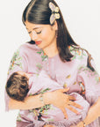 Woman in a floral dress and butterfly hair accessory holding a baby