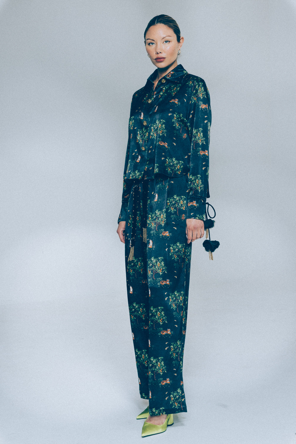 Woman wearing a dark green floral shirt and pant set on a white background