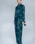 Woman wearing a dark green floral shirt and pant set on a white background