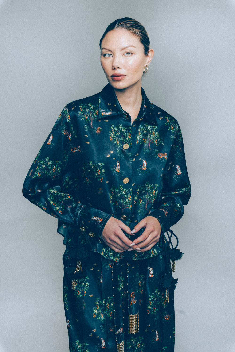 Woman wearing a dark floral patterned outfit against a plain background