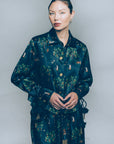 Woman wearing a dark floral patterned outfit against a plain background