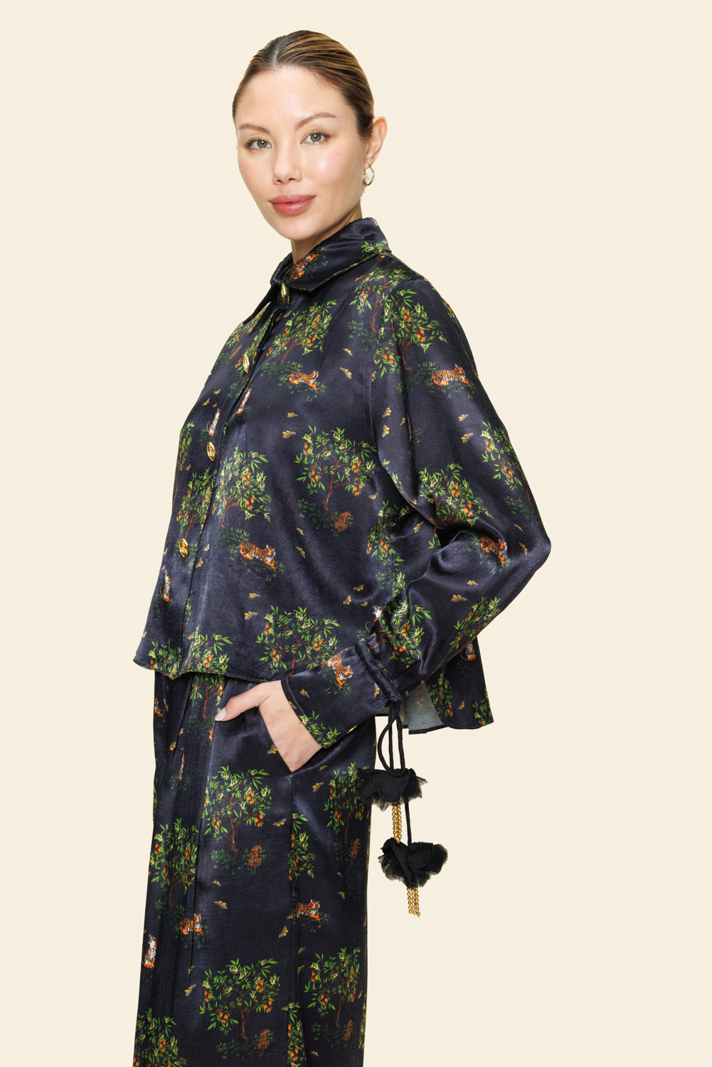 Person wearing a dark floral shirt with tassels on a light background