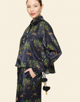 Person wearing a dark floral shirt with tassels on a light background