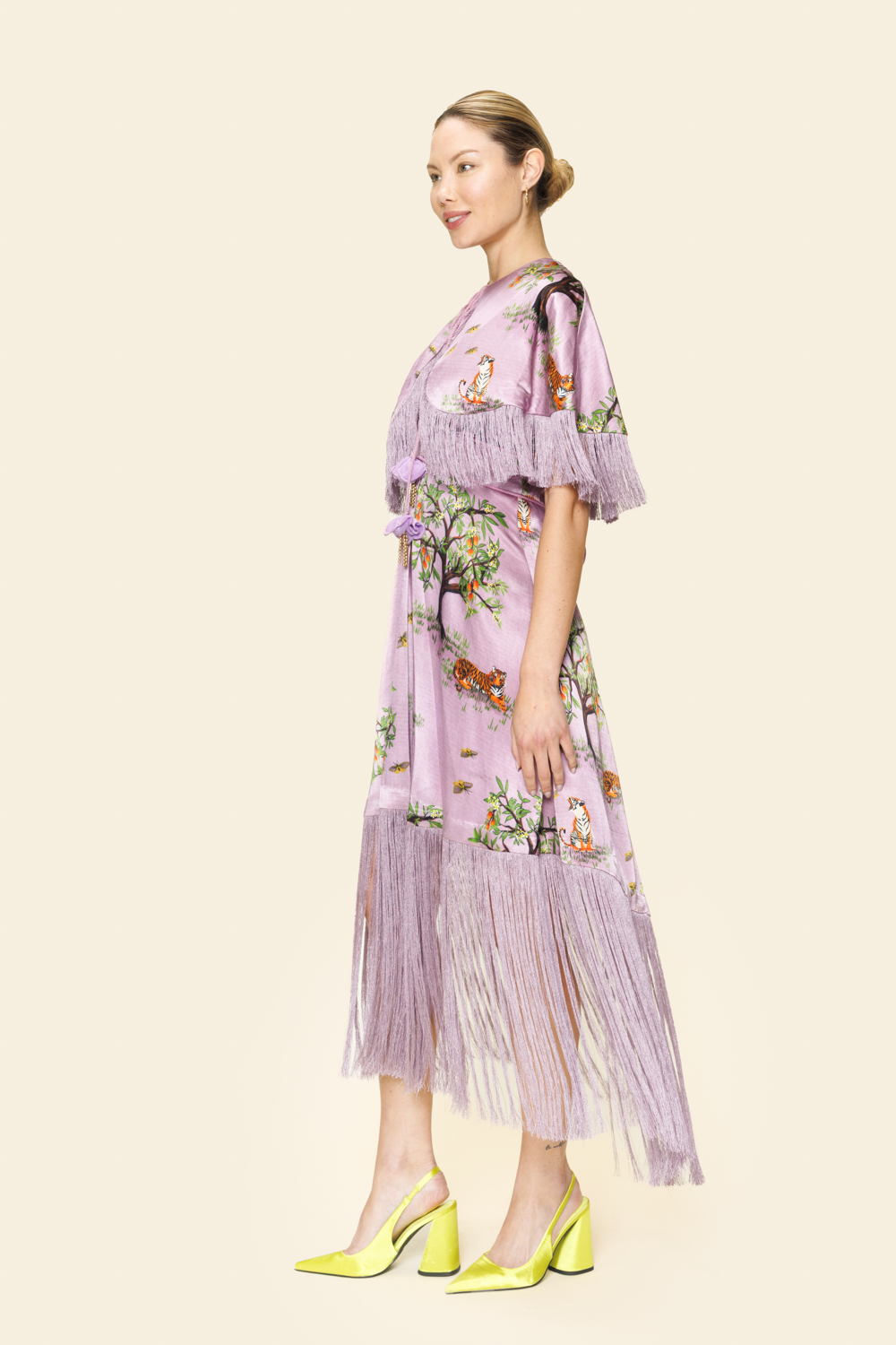 Woman wearing a purple floral dress with fringe details on a beige background