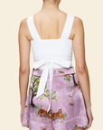 Person wearing a white top and pink floral shorts on a light background
