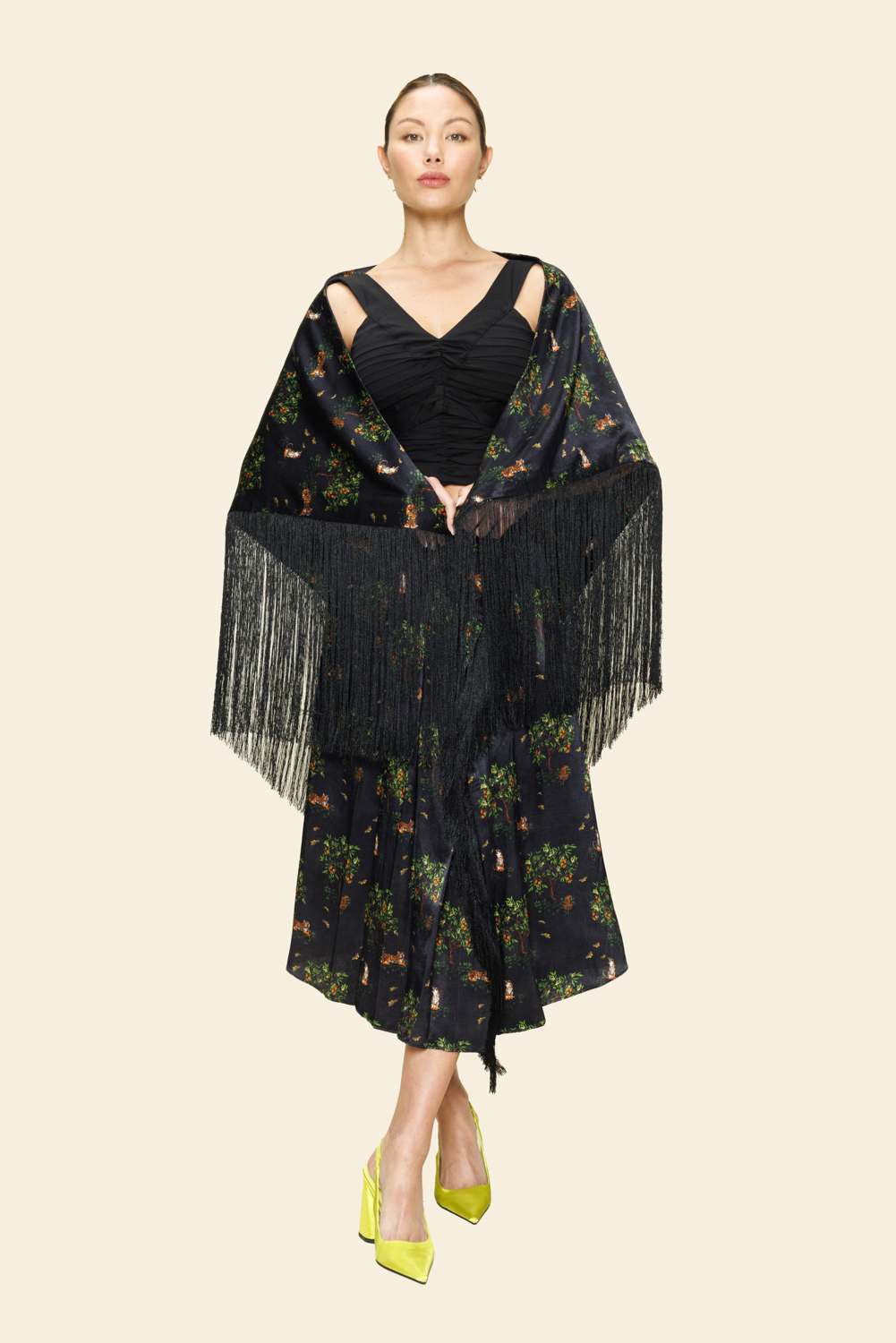 Woman wearing a black floral dress with fringe details on a plain background