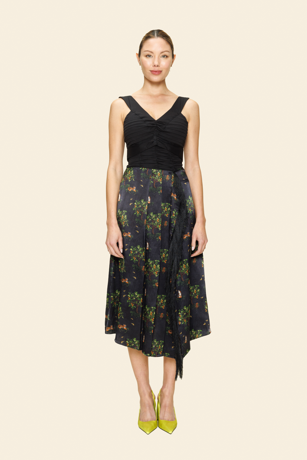 Woman wearing a black top and floral skirt on a plain background