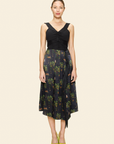 Woman wearing a black top and floral skirt on a plain background