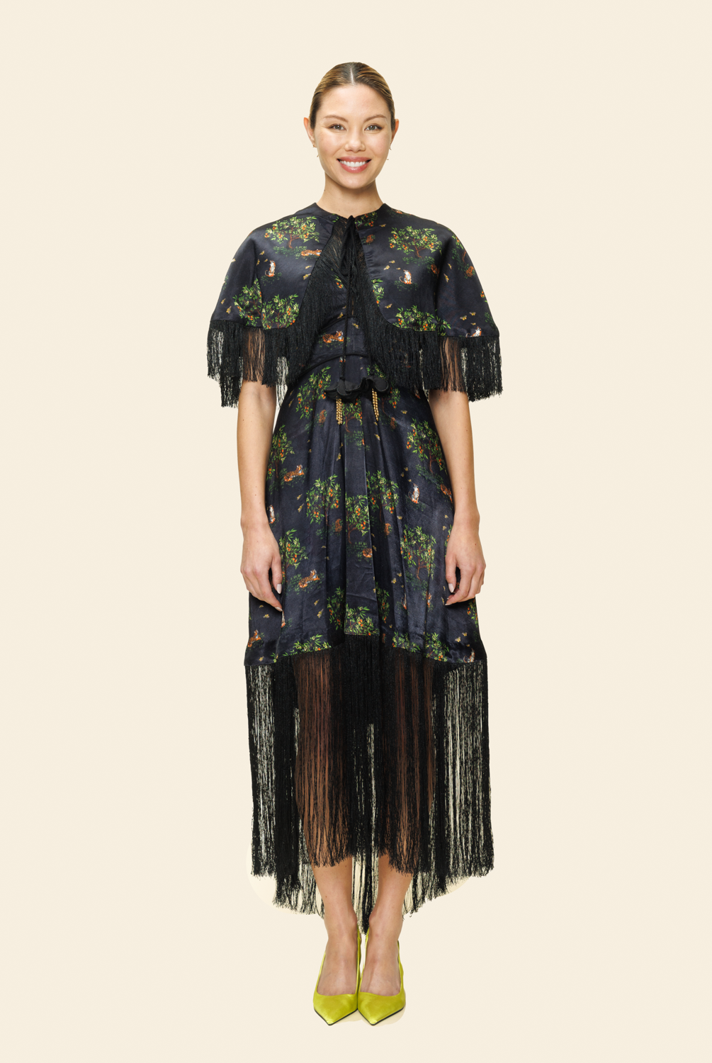 Woman wearing a floral dress with fringe details on a plain background